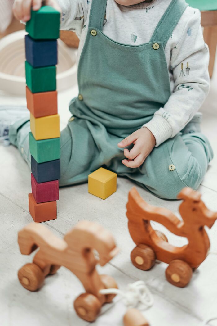 Child playing with colorful blocks and wooden toys, symbolizing moments babysitters realize unusual lives.