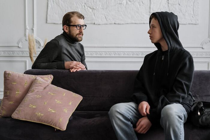 Two people having a serious conversation on a sofa, highlighting job secrets sharing.