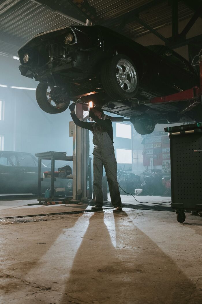 Mechanic working on a car lift in a garage, highlighting transformation from best friends to strangers.