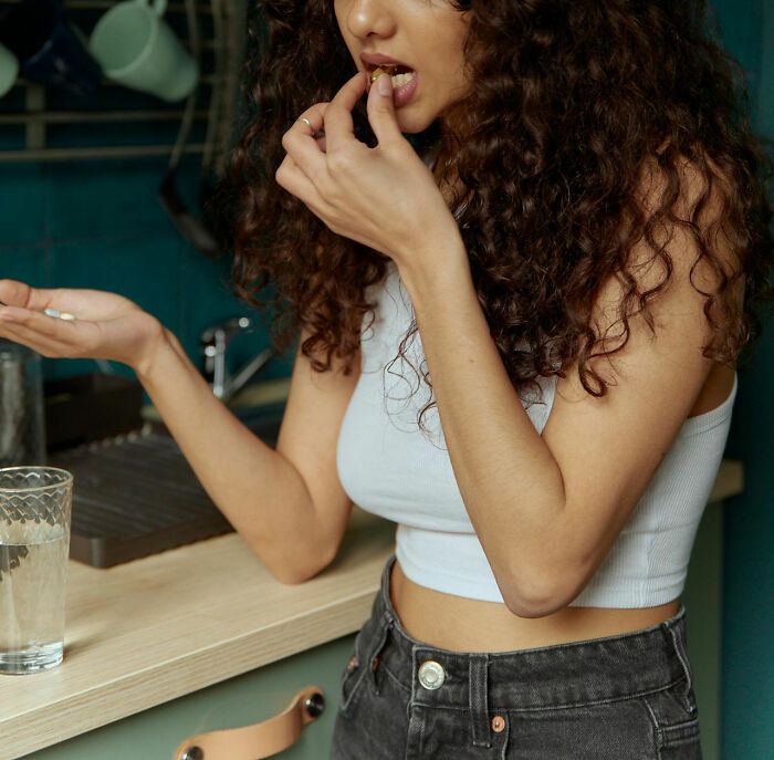 Woman standing in kitchen with a puzzled look, highlighting the moment of realizing dating an idiot.