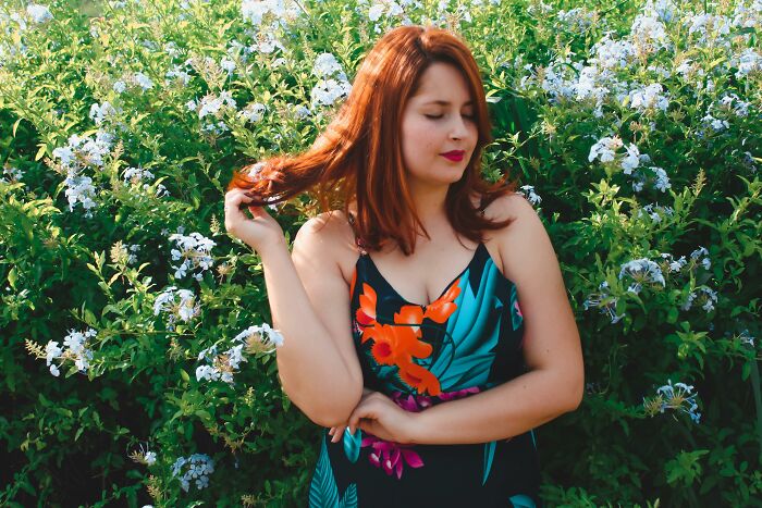 Woman in floral dress standing confidently in field, representing WomenInMaleFields trend.