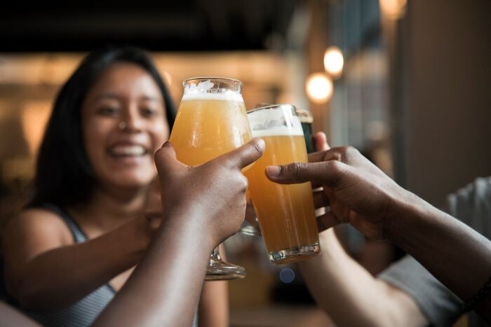 People toasting with beer in a lively setting, emphasizing the difference exercise can make on health and well-being.