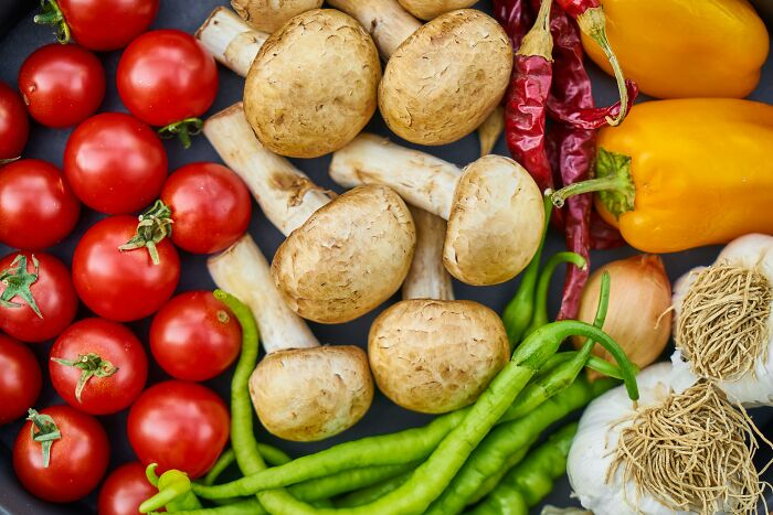 Colorful array of fresh vegetables including tomatoes, mushrooms, and peppers, showcasing everyday produce.