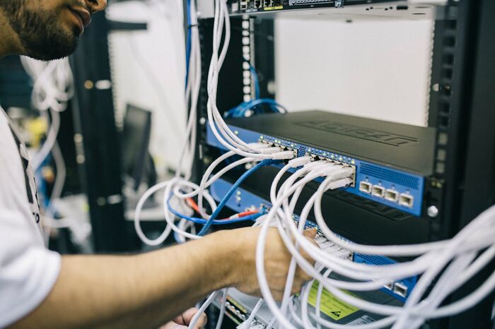 Man organizing cables in a server room, revealing job secrets in technology.