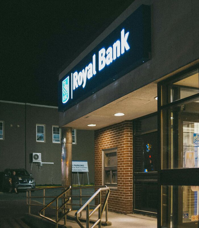 Exterior of Royal Bank branch at night, featuring illuminated signage and brick facade.