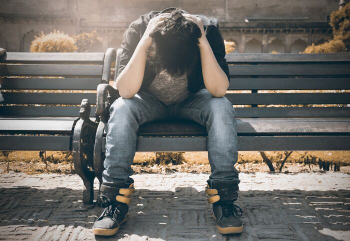 Casino employee sitting on a bench, holding head in hands, revealing behind-the-scenes stress and challenges.