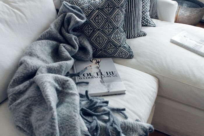 Cozy couch with a gray throw, chic cushions, and a magazine, showcasing frugal home comfort and style.