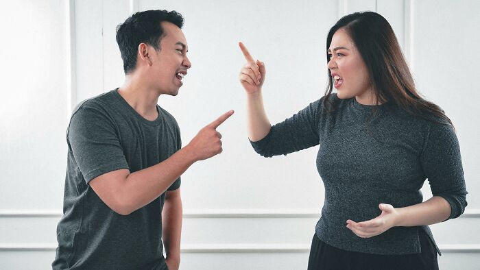 Man and woman engaged in a lively discussion, illustrating the "WomenInMaleFields" trend, both pointing fingers.