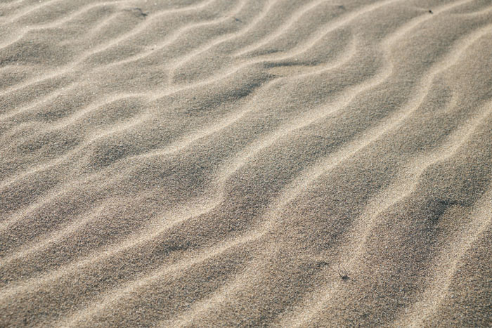 Wavy patterns in sand under sunlight, displaying rare textures in everyday nature.