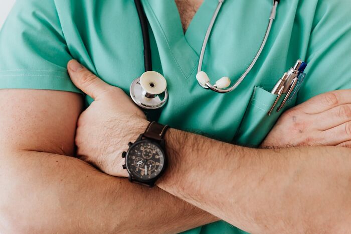 Doctor in green scrubs with stethoscope and watch, emphasizing exercise advice.