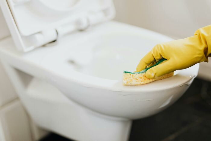 Gloved hand cleaning a toilet, illustrating a challenging job experience.