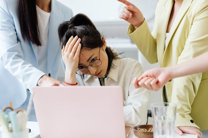 Person stressed at a desk, surrounded by colleagues, highlighting exercise as key advice from doctors.