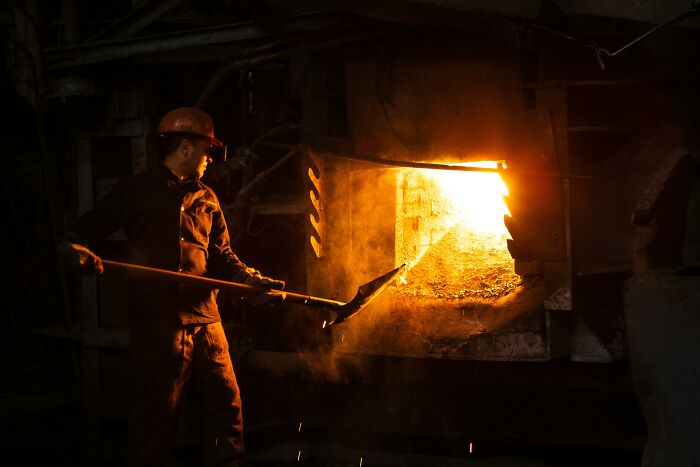 Worker handling molten metal in a foundry, illustrating one of the worst jobs people have experienced.