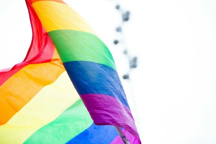 A rainbow flag waves against a bright sky, symbolizing pride and inclusivity.