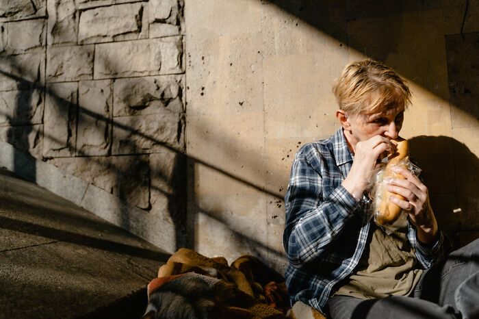 Person in plaid shirt sitting outdoors, eating a sandwich in sunlight, illustrating job secrets in everyday life.