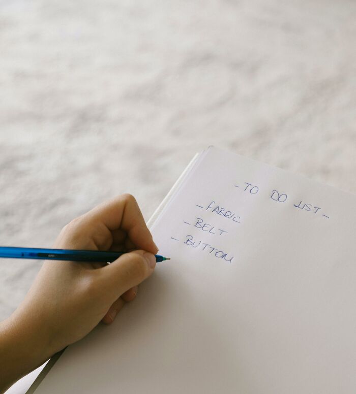 Handwriting a to-do list with items like fabric, belt, button, showcasing everyday productivity in action.