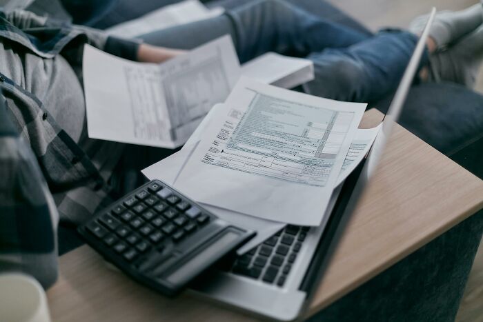 Calculator and paperwork on a laptop, symbolizing the concept of people sharing secrets through financial documents.