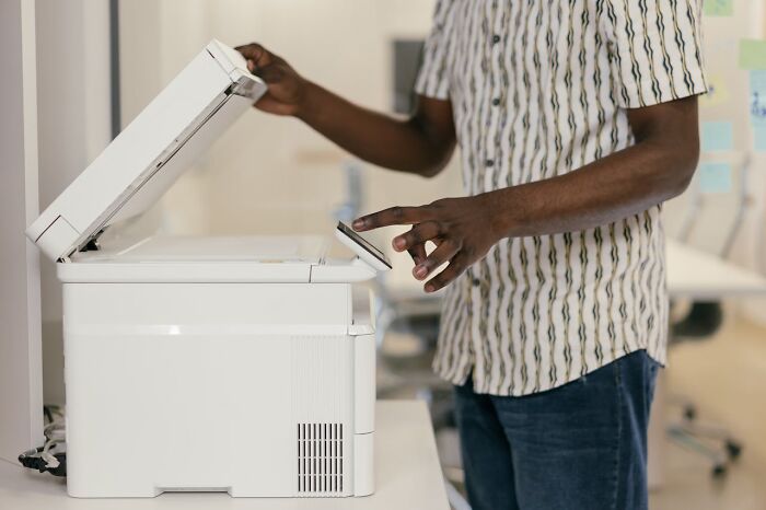 Person using a copier in an office setting, illustrating a sudden job termination.