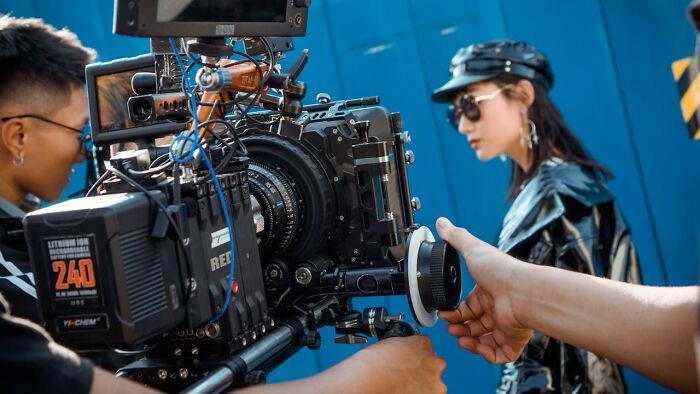 "People working on a film set showing the less fun side of 'fun' jobs, focusing on camera equipment and crew."