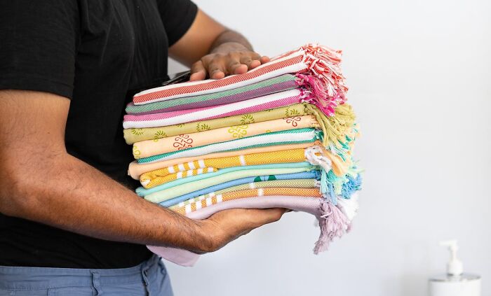 Person holding a stack of colorful, fresh towels promoting good hygiene habits.