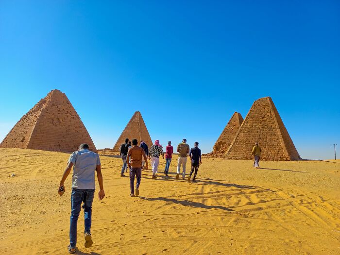 People walking towards ancient pyramids under a clear blue sky, demonstrating rare everyday facts in a historical setting.