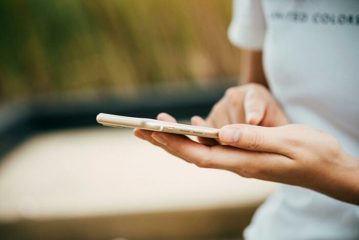 Person using smartphone outdoors, capturing the "WomenInMaleFields" trend.