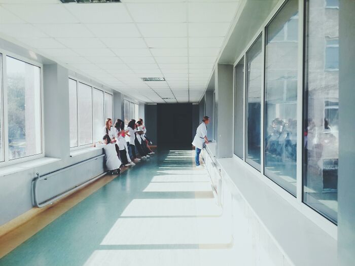 Group of nurses in a hospital corridor, coincidentally gathered in sunlight streaming through large windows.