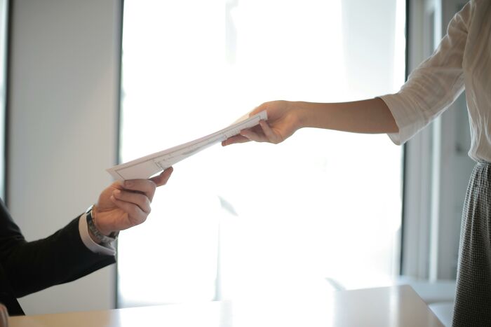 Two people exchanging documents in a bright office, illustrating coincidences in a global setting.