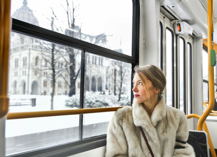 Woman in a fur coat enjoying peace and quiet on a snowy tram ride.