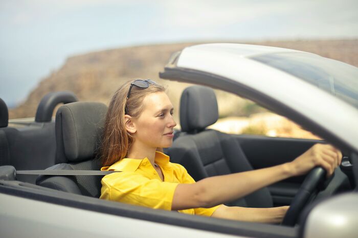 Woman driving a convertible in a scenic setting, representing the WomenInMaleFields trend.