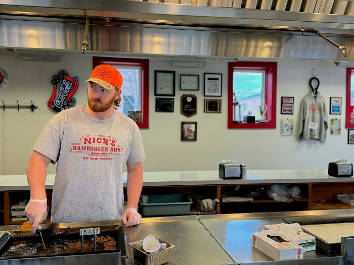 Person in a burger shop kitchen wearing an orange cap, part of the WomenInMaleFields trend showcasing diverse roles.