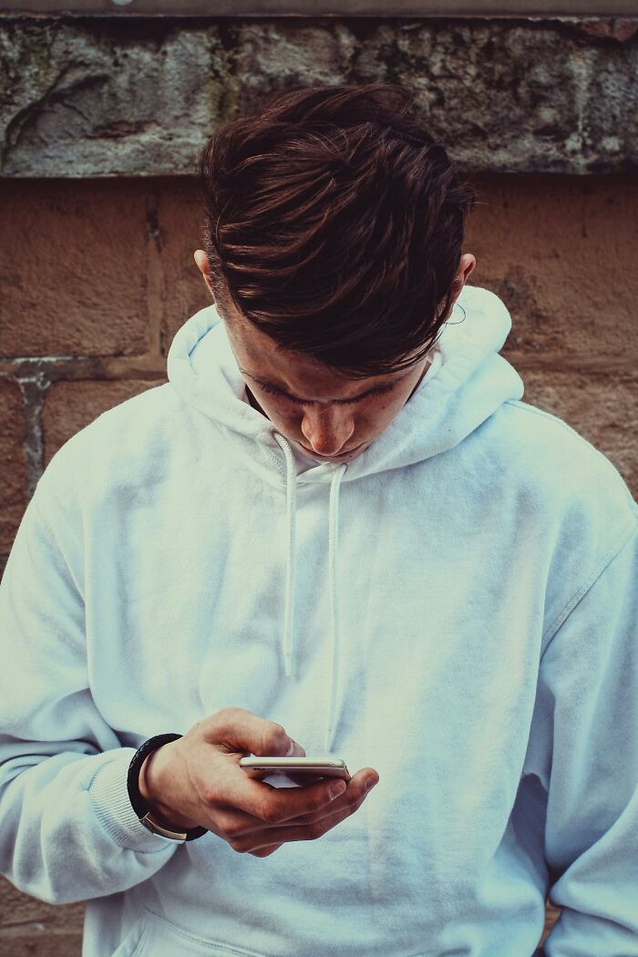 Person in a white hoodie looking down at phone, representing the theme of best friends becoming strangers.