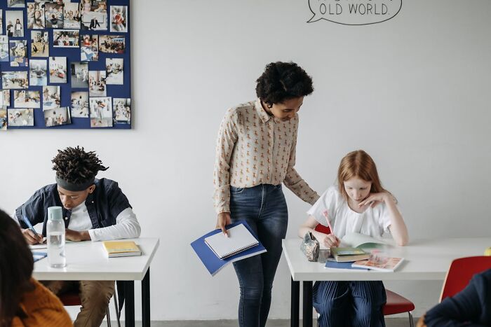 Teacher assisting students in a classroom, highlighting job secrets in an educational setting.