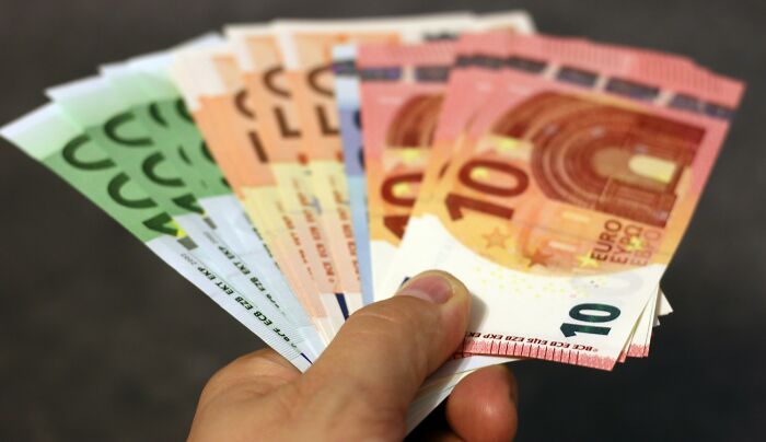 A hand holding various euro banknotes.