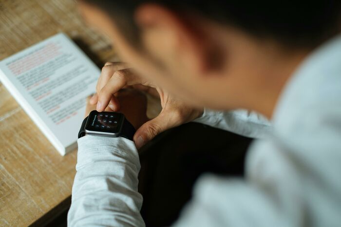 Person checking the time on a smartwatch while reading, representing a modern lifestyle.