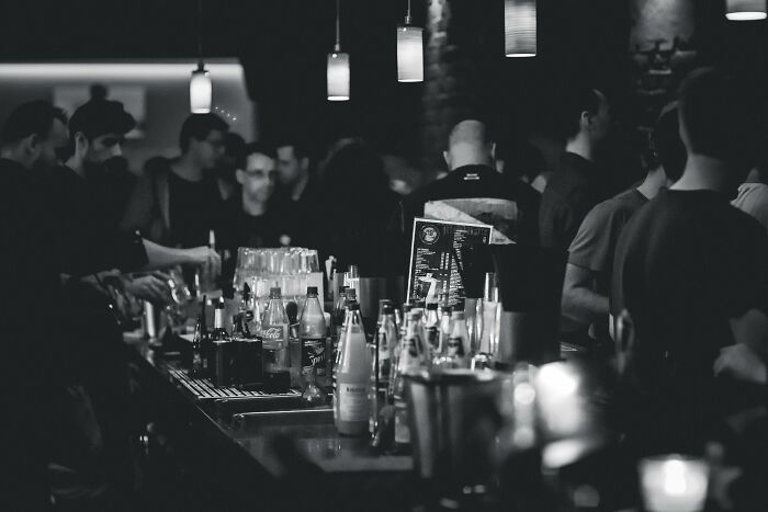 A crowded bar with dim lighting, showcasing a lively nightlife atmosphere, drinks, and social interactions.