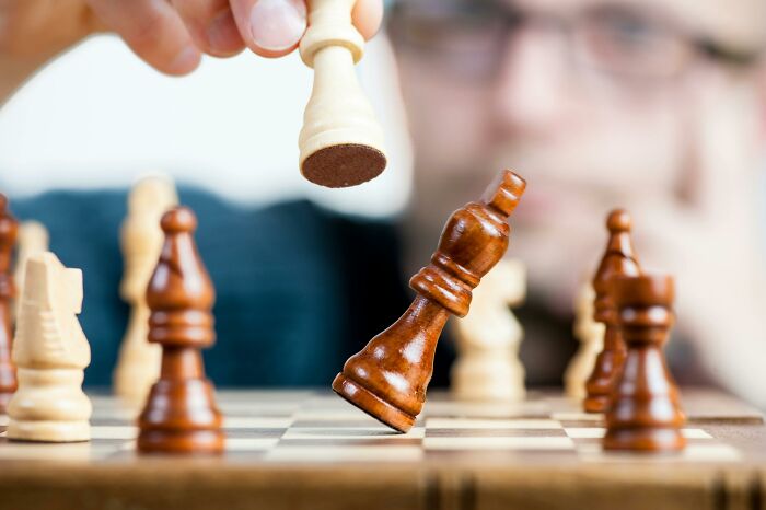 Person playing chess, moving a white pawn, with a focused expression.