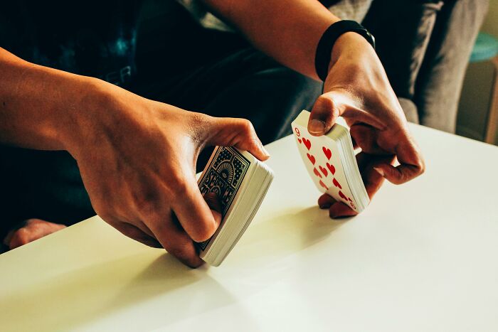 Person shuffling playing cards, demonstrating a rare everyday skill at a table.