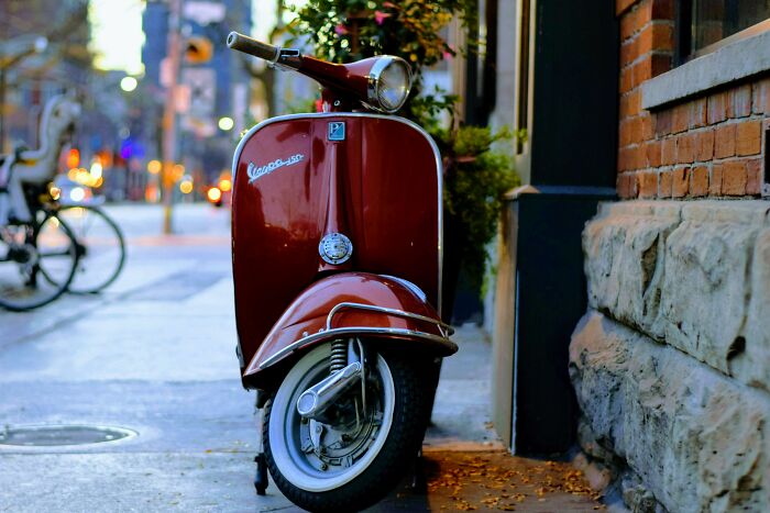 A red Vespa parked on an urban sidewalk, capturing an unexpected moment.