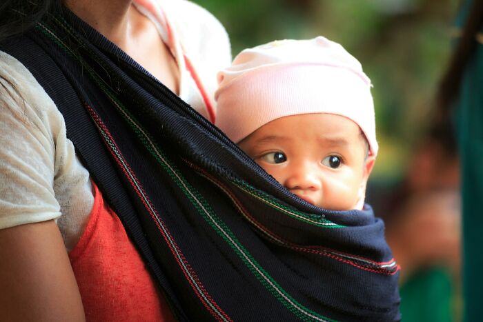 Woman carrying a baby in a sling, highlighting the "WomenInMaleFields" trend.