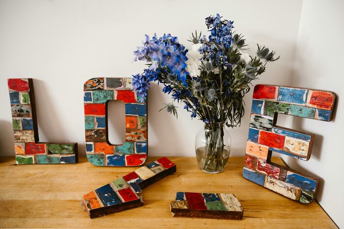 Colorful letters spelling "LOVE" with blue flowers in a vase.