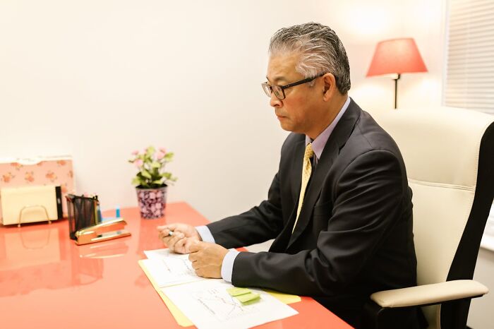 Doctor in an office, reviewing paperwork at a red desk, emphasizing exercise as key advice.