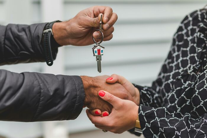 Exchanging house keys in a handshake, symbolizing trust in professions.