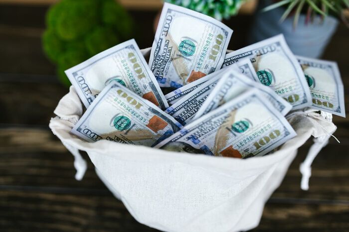 A bag overflowing with cash on a wooden table, symbolizing abrupt job loss and financial impact.