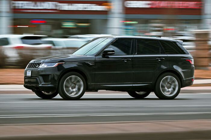 Luxury SUV driving on a city street, symbolizing wealth and privilege among rich kids.