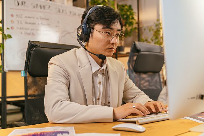 A person in an office wearing headphones, focused on a computer screen, representing remote work challenges.