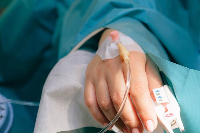 Patient's hand with an IV drip, revealing secret medical practices in a hospital setting.