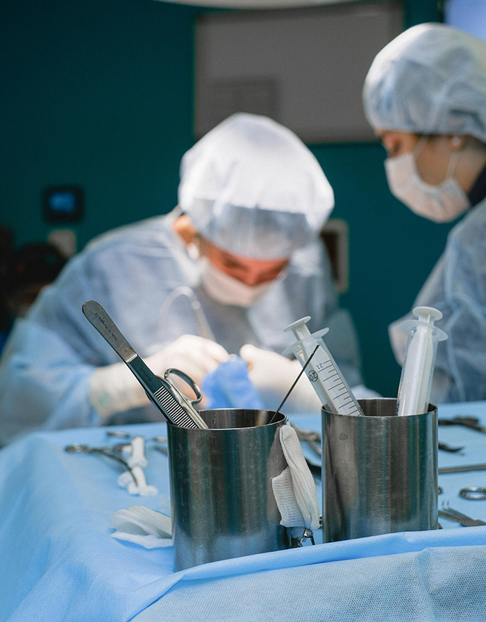 Surgeons performing surgery with instruments and syringes in focus on a sterile table.