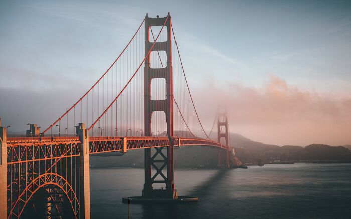 Golden Gate Bridge enveloped in mist at sunrise, secrets of engineering marvels.