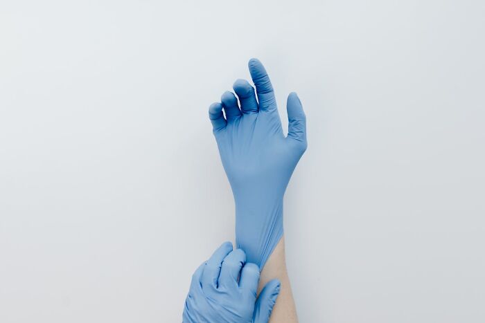 Person putting on blue gloves, demonstrating good hygiene habits.